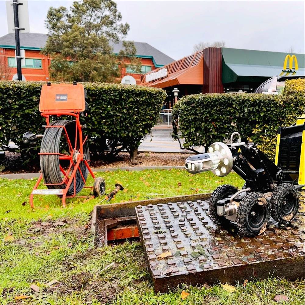 CCTV crawler robot and survey equipment set up outside a McDonald's restaurant