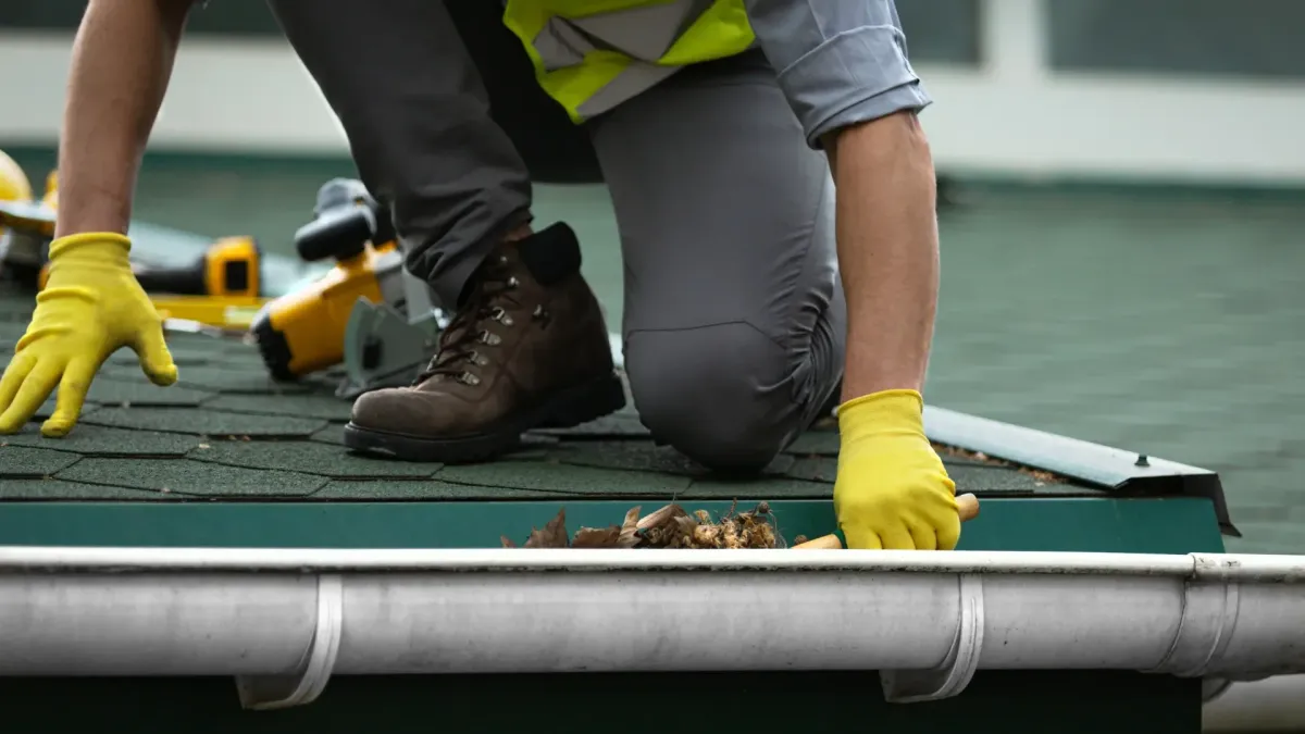 Contractor inspecting a home’s gutter system before winter rain in Los Angeles.