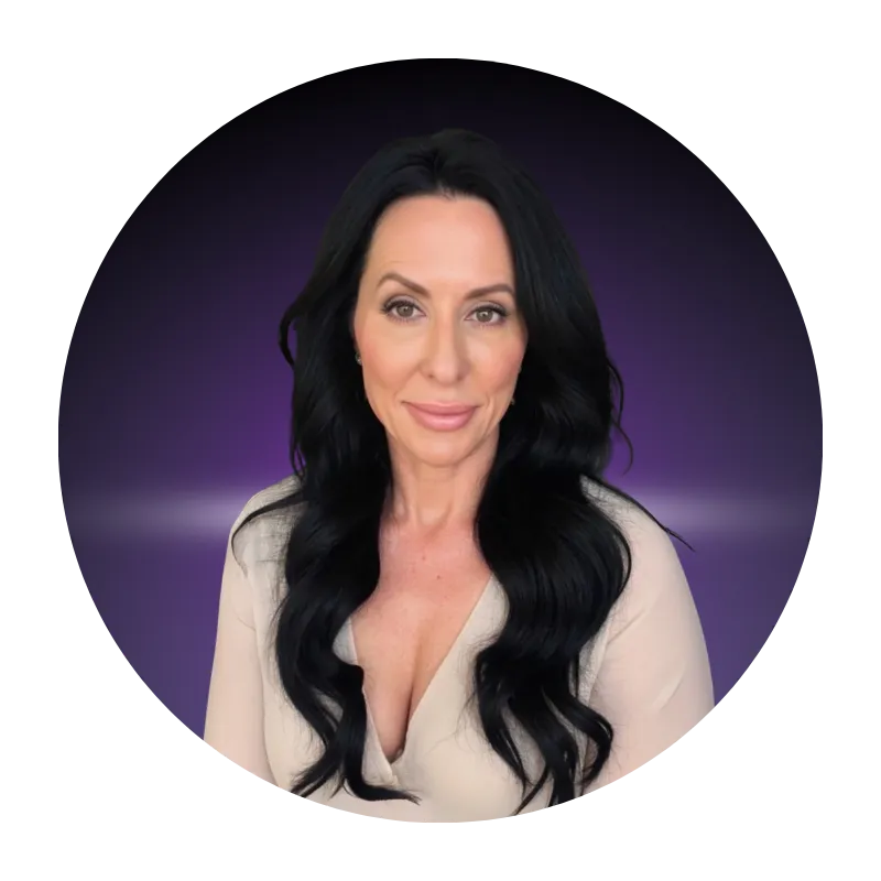 Michelle Feuerstein headshot, sex and relationship coach, long black hair, light top, smiling against dark purple background