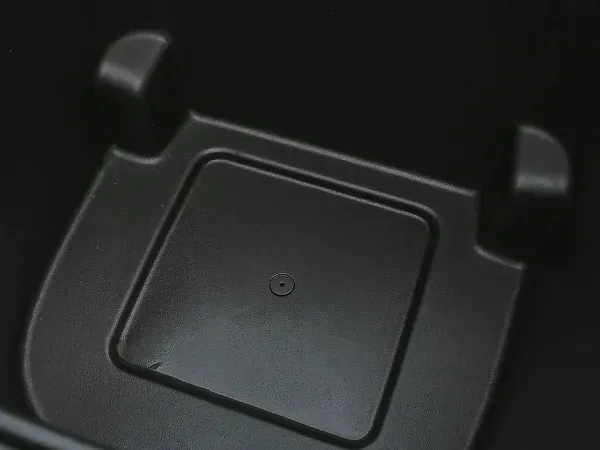 A close-up view of a matte black plastic organizer or box with a rectangular insert and circular indentation.