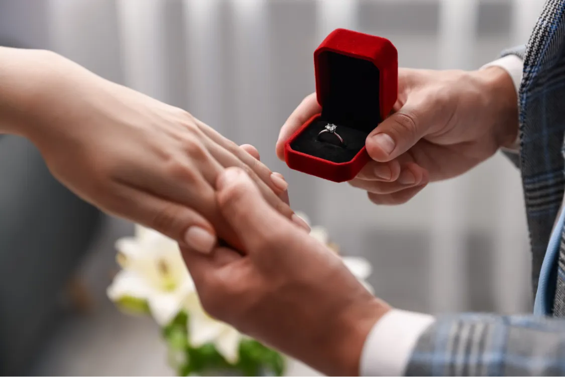 Man proposing with diamond engagement ring in red box
