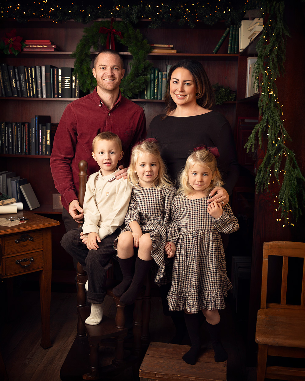 En familj står framför en bokhylla i en vackert julig miljö hos Feicia på Little Moments.