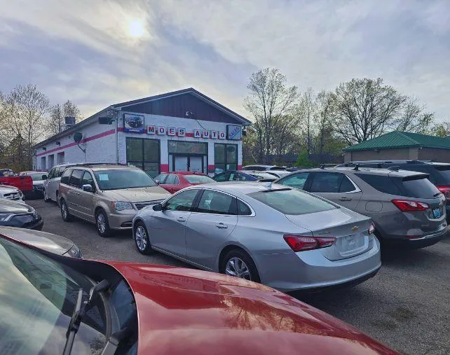 Front view of MOES Auto Sales & Services in Louisville, KY, featuring the main entrance, used cars for sale, and the side of the auto repair shop.