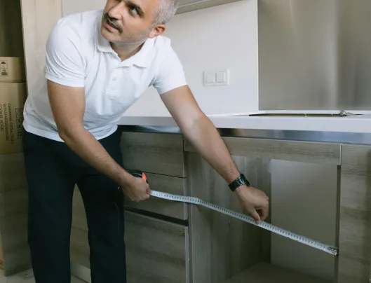 Man measuring kitchen cabinets