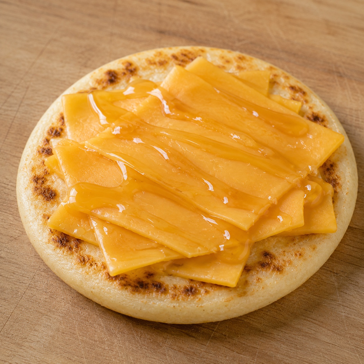 Arepa topped with slightly melted mild cheddar and a honey drizzle