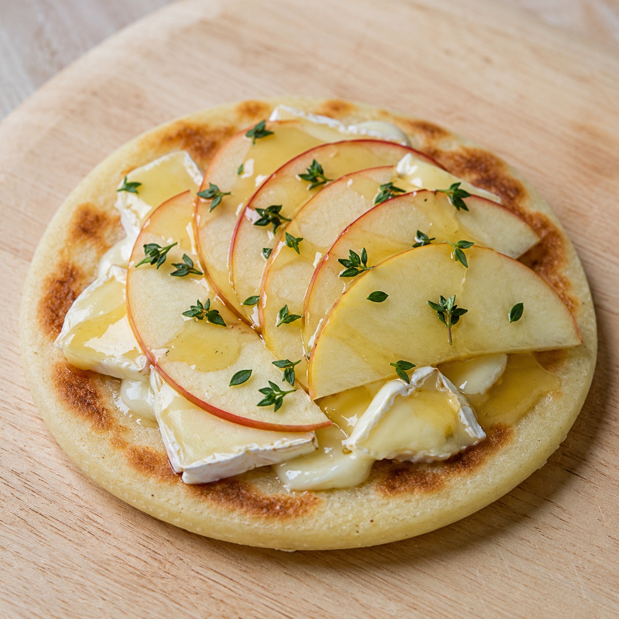 Arepa topped with softened brie, apple slices, honey and thyme