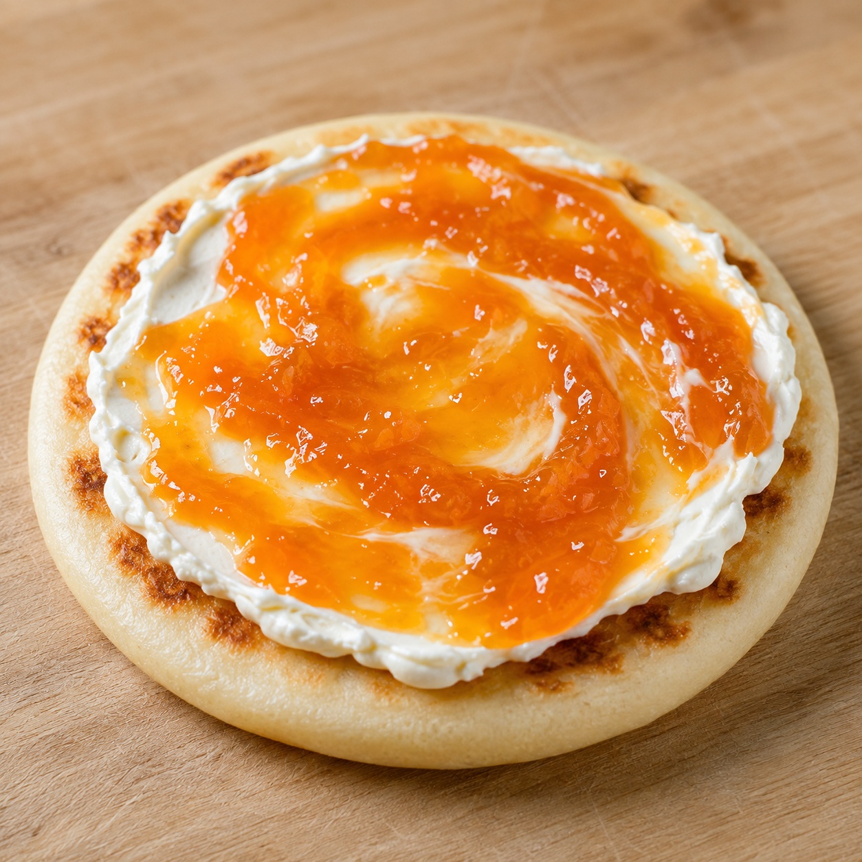 Arepa spread with cream cheese and bright orange apricot jam