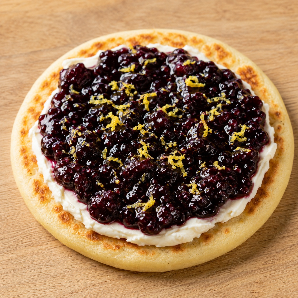 Arepa spread with cream cheese, dark blackberry jam and lemon zest
