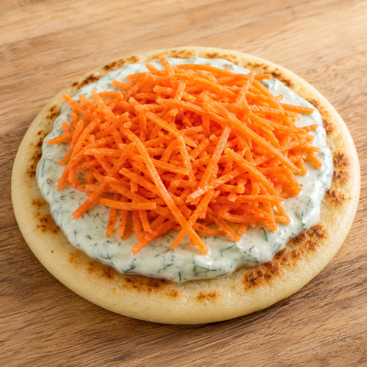 Arepa spread with herby yogurt ranch and topped with shredded carrots