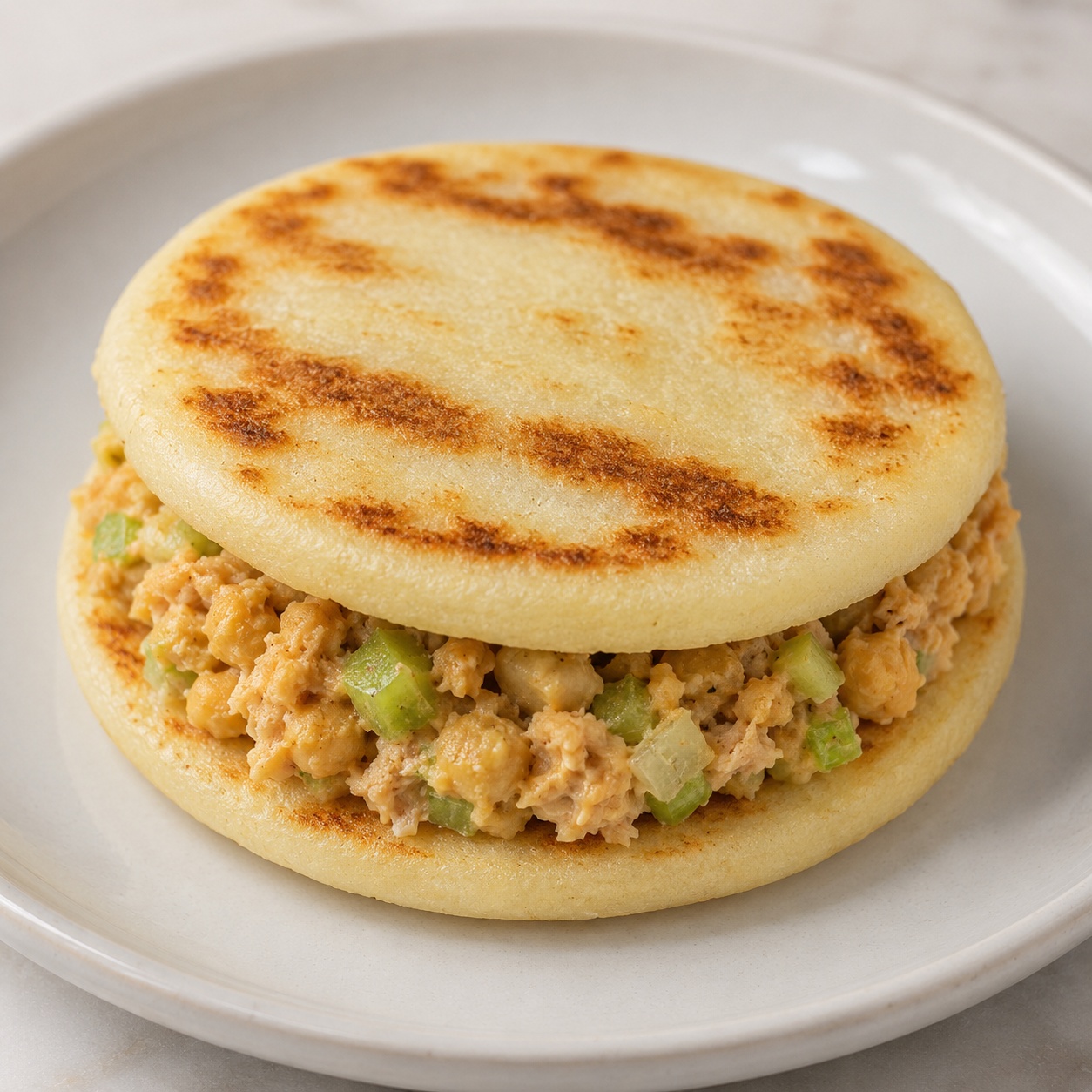 Two arepas sandwiched with mashed chickpea 'tuna' salad