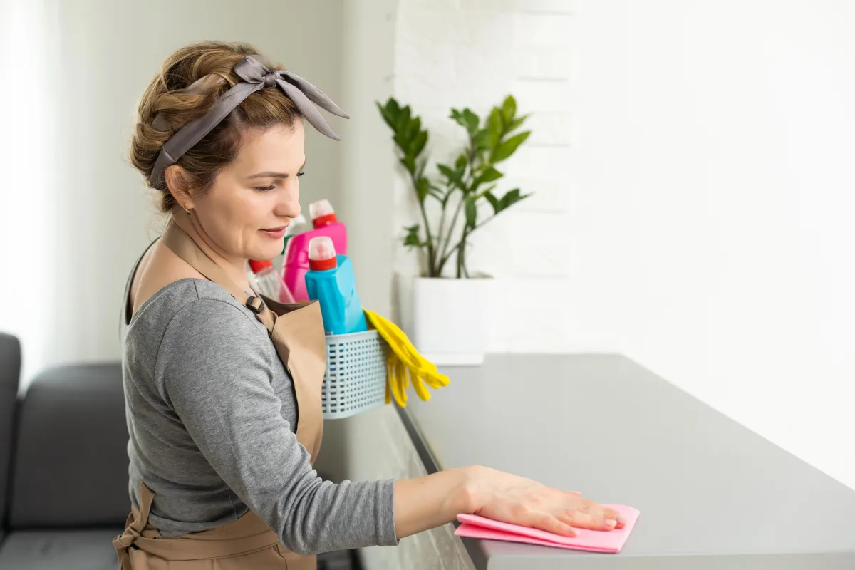 Female cleaning professional wiping down a surface in a residential home, ensuring a spotless and well-maintained space.