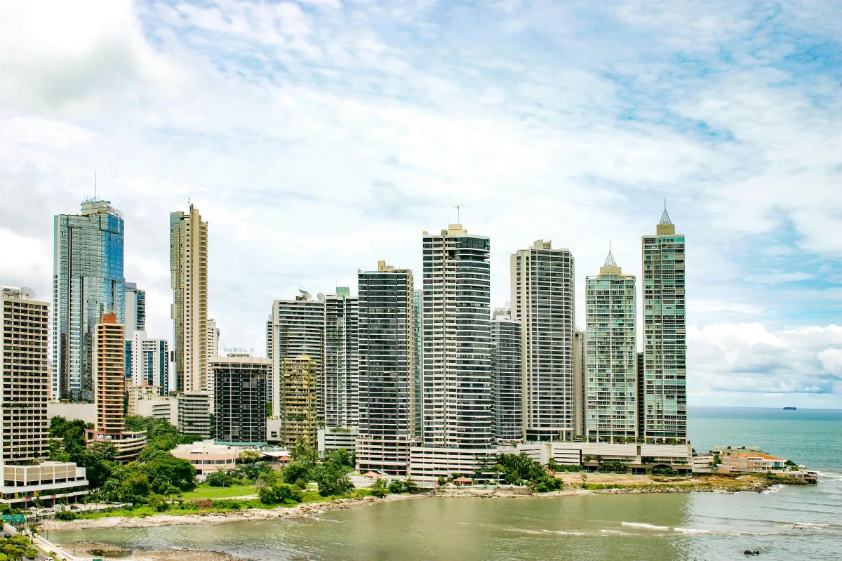 Modern Panama City skyline with high-rise towers along the waterfront under a blue sky.