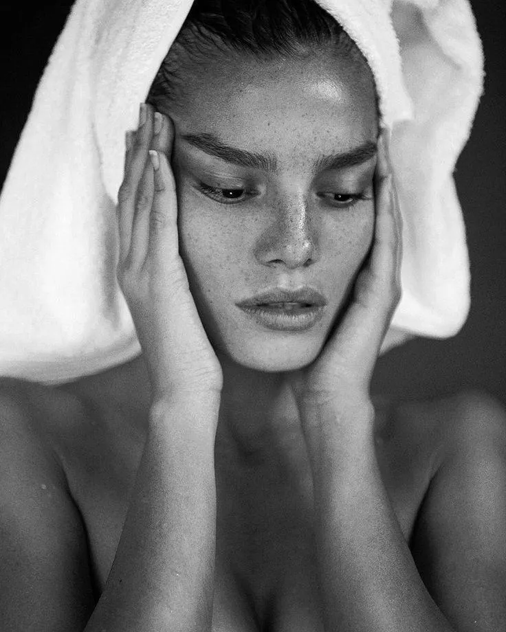 Woman applying facial cleanser in front of mirror