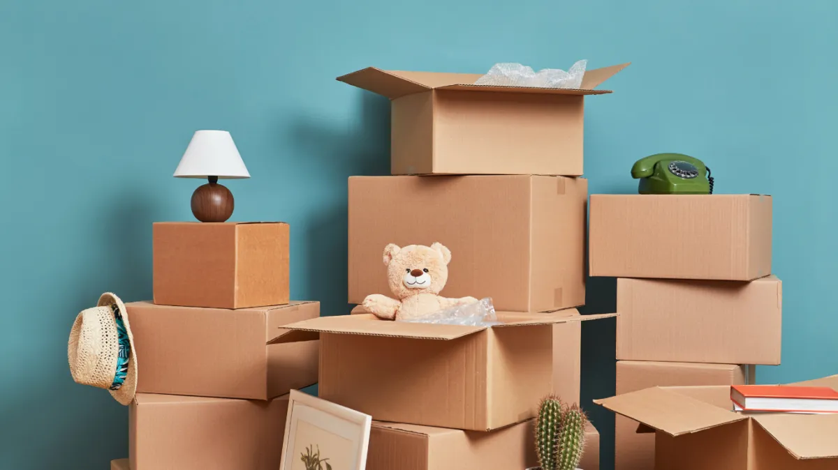 a Stack of moving boxes in a room with a light blue wall background
