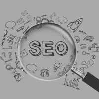 a magnifying glass looking at the words "SEO" surrounded by relevant search engine optimization and computer symbols