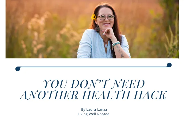 Laura Lanza smiling in a golden field at sunset with a yellow flower in her hair, featured on the blog post “You Don’t Need Another Health Hack” by Living Well Rooted.