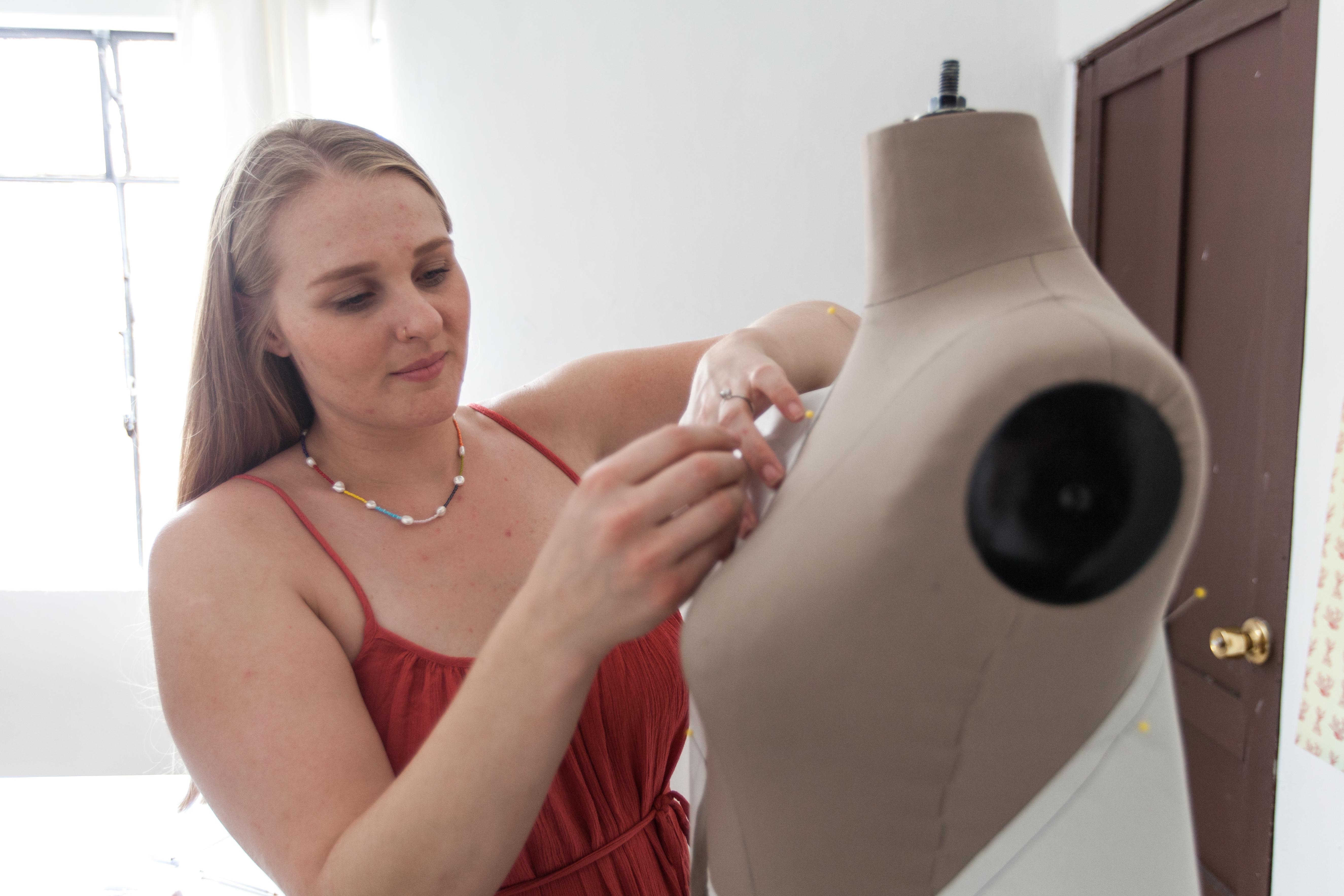 A woman pinning fabric onto a mannequin