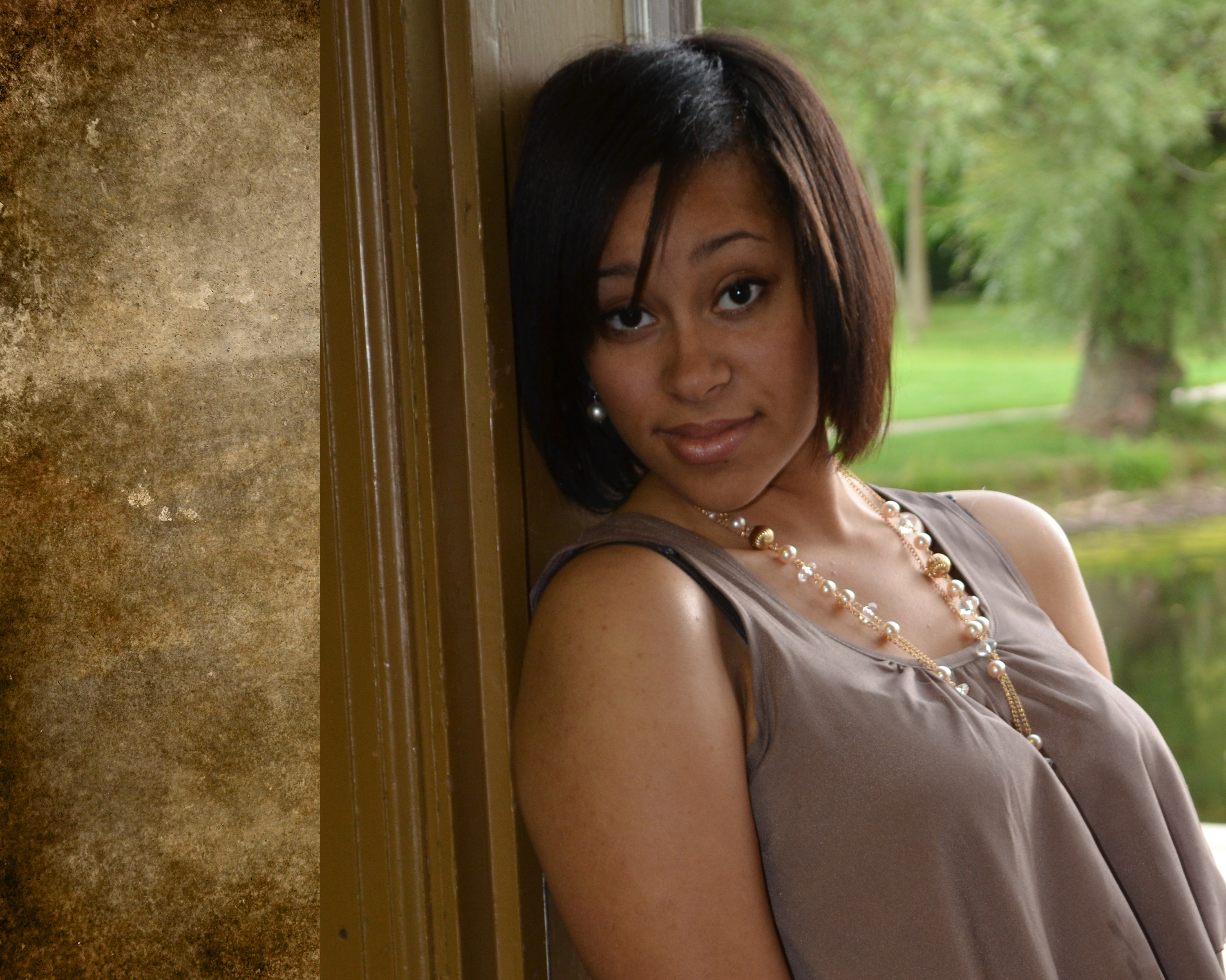 A senior student poses confidently in a sunlit park, wearing a graduation cap and gown, surrounded by green trees and a soft-focus background, expressing pride and anticipation for the future.