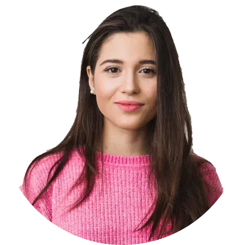 Smiling woman with long brown hair wearing a pink sweater.