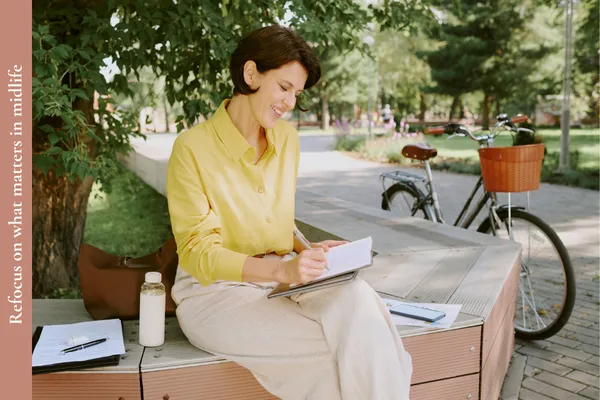 A woman pausing on her bicycle ride to write down what matters to her in midlife