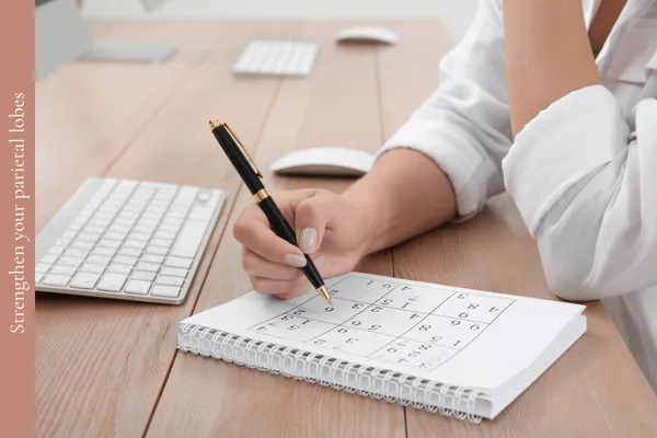 Woman sitting at a desk doing a suduko puzzle to strengthen her parietal lobes