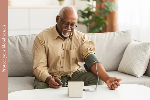 Older man checking his blood pressure at home to help protect his blood vessels and cardiovascular health.