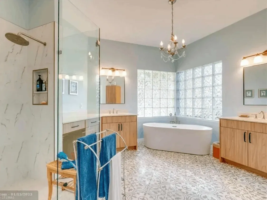 Renovated kitchen in Coral Springs FL with white cabinetry, quartz countertops, stainless steel appliances, and pendant lights.
