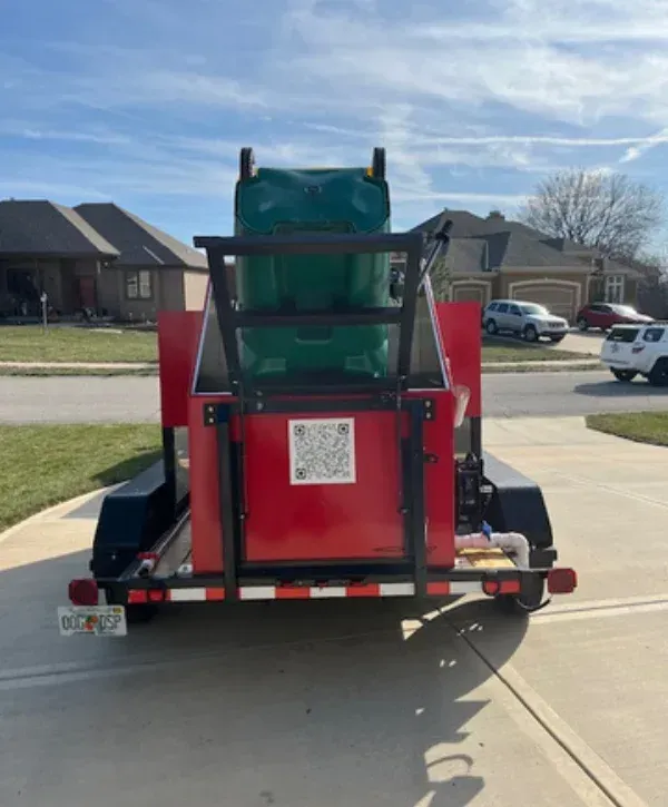 A bright red trailer with "Trash Bin Cleaning" branding and a washing mechanism on the side.