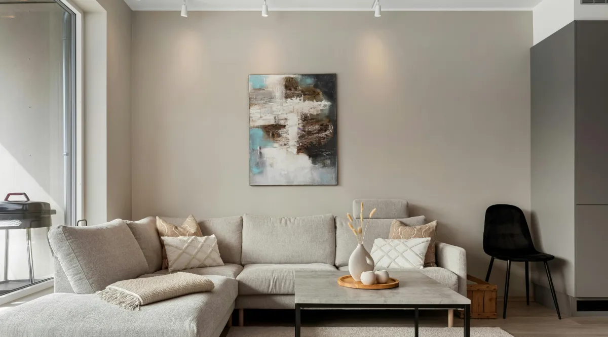 Modern living room remodel featuring stone fireplace, neutral sectional sofa, accent chairs, and large sliding glass doors leading to a landscaped backyard