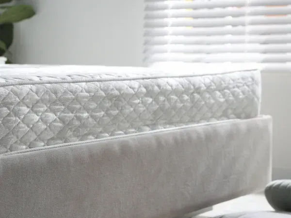 A man in a green uniform and shoe covers cleans a large stone floor in a bright, modern living room with a floor cleaner.