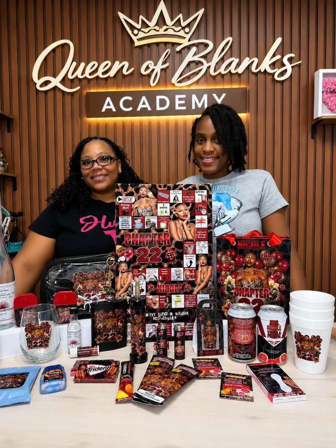 Party Plug Workshop hosts standing behind a merch table at the event
