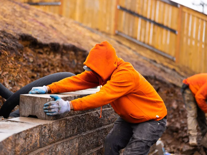 Bell Gardens team member installing retaining wall