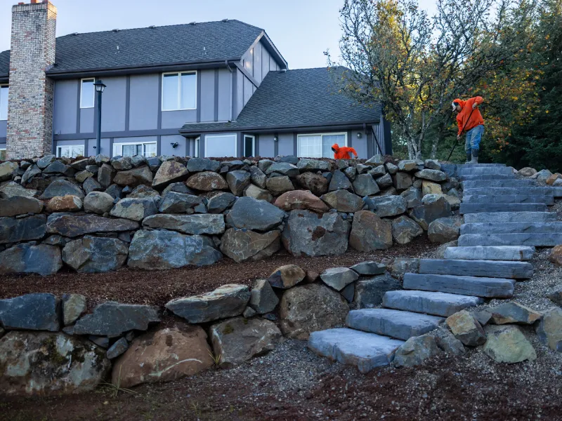 stone stairs and terrace stone retaining walls with house and workers in the background