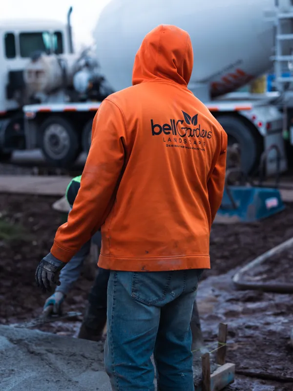 Bell Gardens team member on worksite with cement truck in background