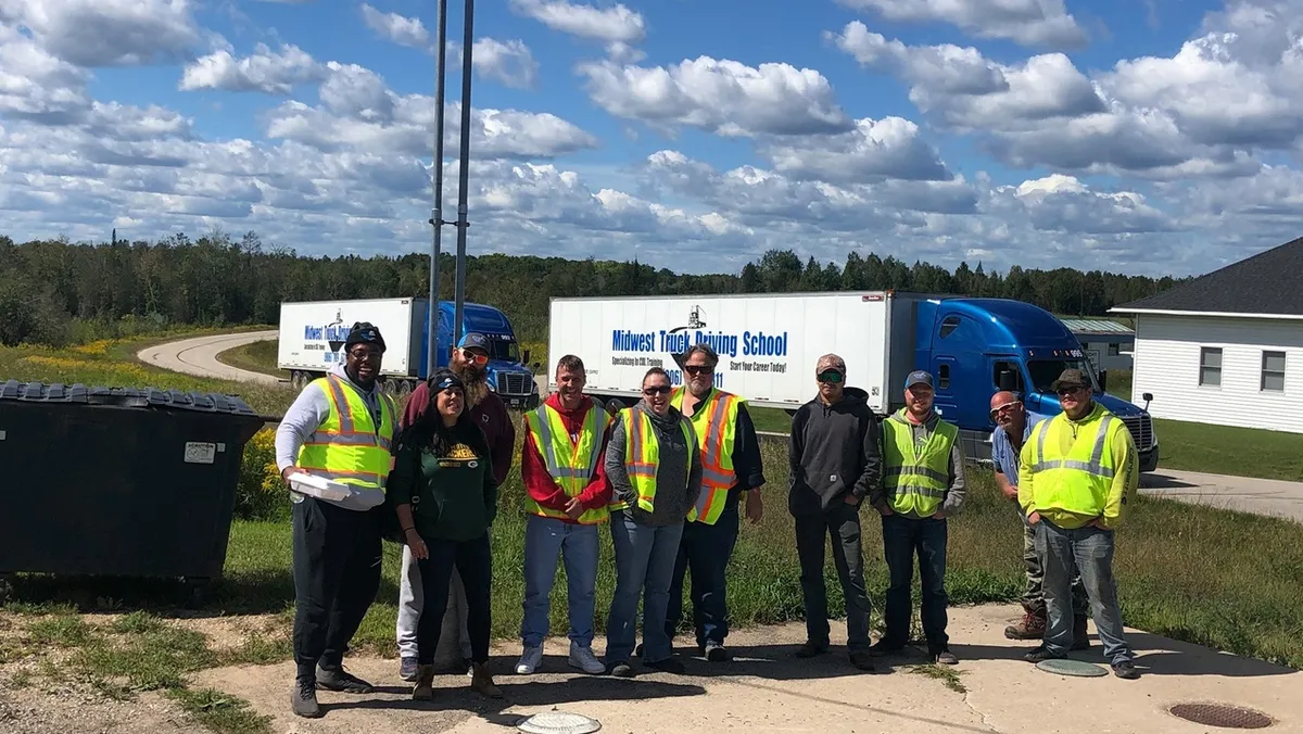Midwest CDL students and instructors with training trucks