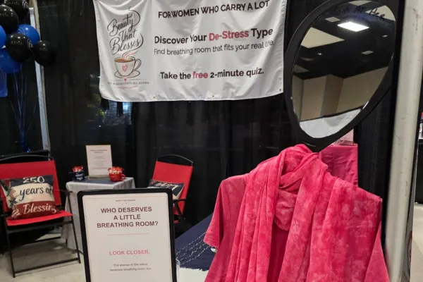 Mirror-covered mannequin dressed in pink at the Beauty That Blesses expo booth, representing women who keep showing up while quietly carrying stress and full lives.
