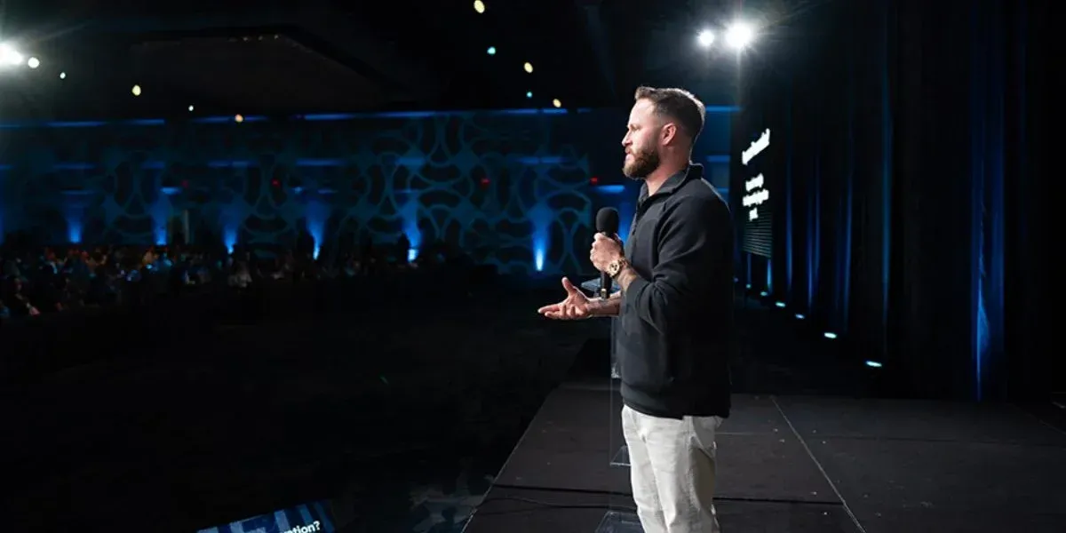 Justin Brock speaking on stage at a professional conference about Medicare insurance education and agent training systems