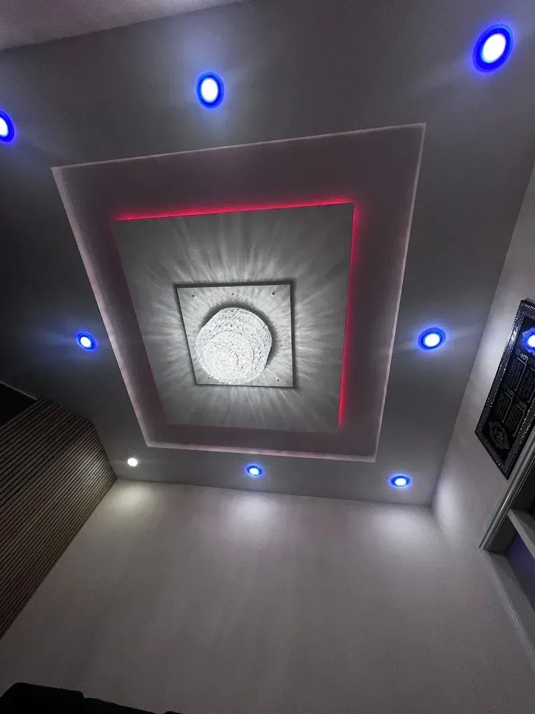 Modern residential ceiling lighting installation in Blackburn featuring recessed blue LED spotlights and a central decorative chandelier