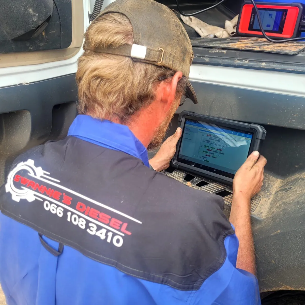 Diesel mechanic performing engine maintenance on a truck in a workshop