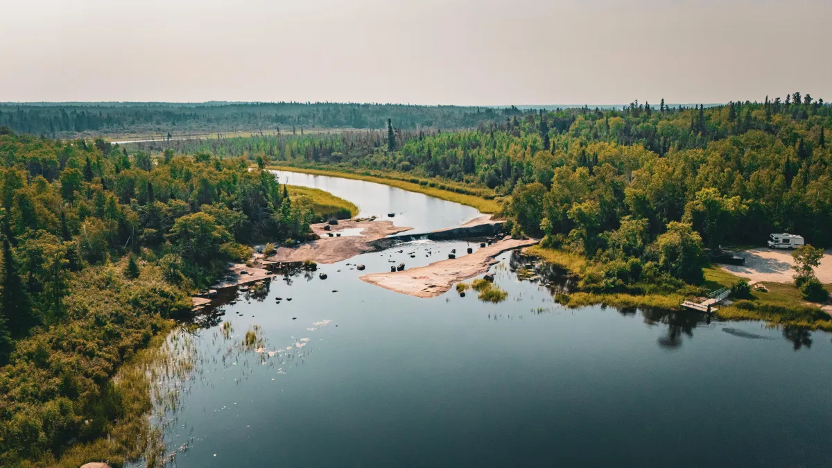 man in black jacket and blue denim jeans standing on rock formation during daytime