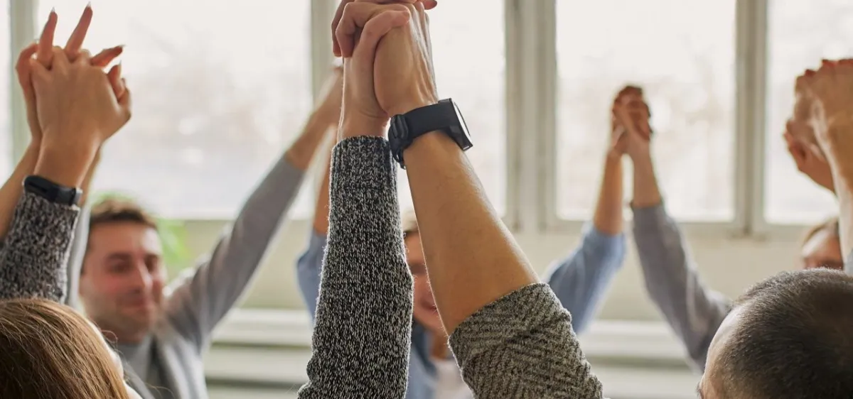 Volunteers and program participants at an outdoor community support event, sharing handshakes and smiles.