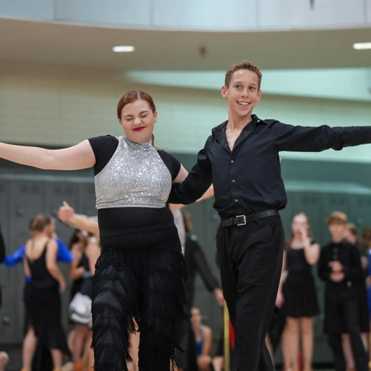 Youth ballroom students smiling and having fun while dancing at a competition