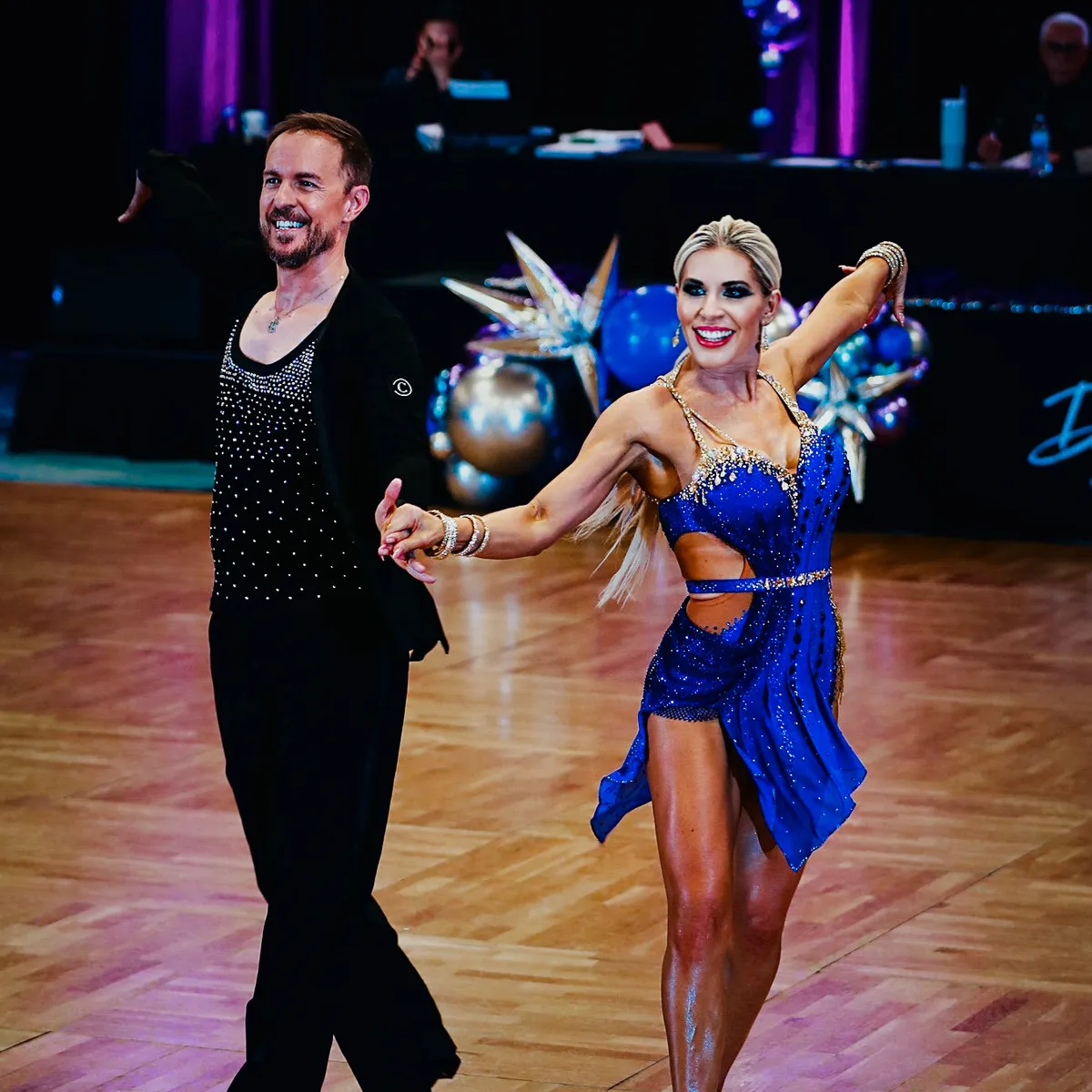 Ballroom instructor and adult student dancing Latin at a competition