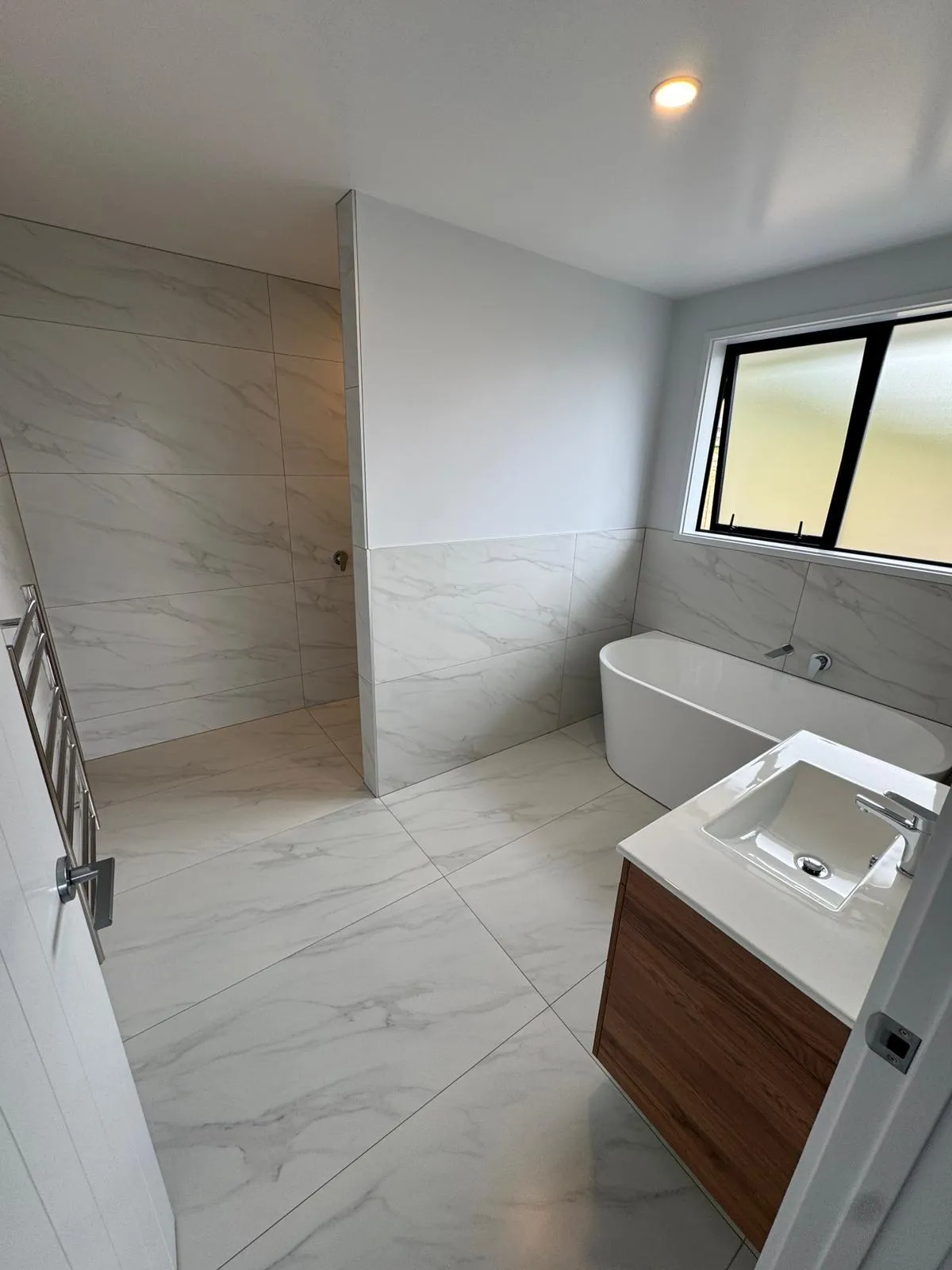 Large format wall and floor tiling installed in a modern residential bathroom by Remarkable Contracting in Hawke's Bay