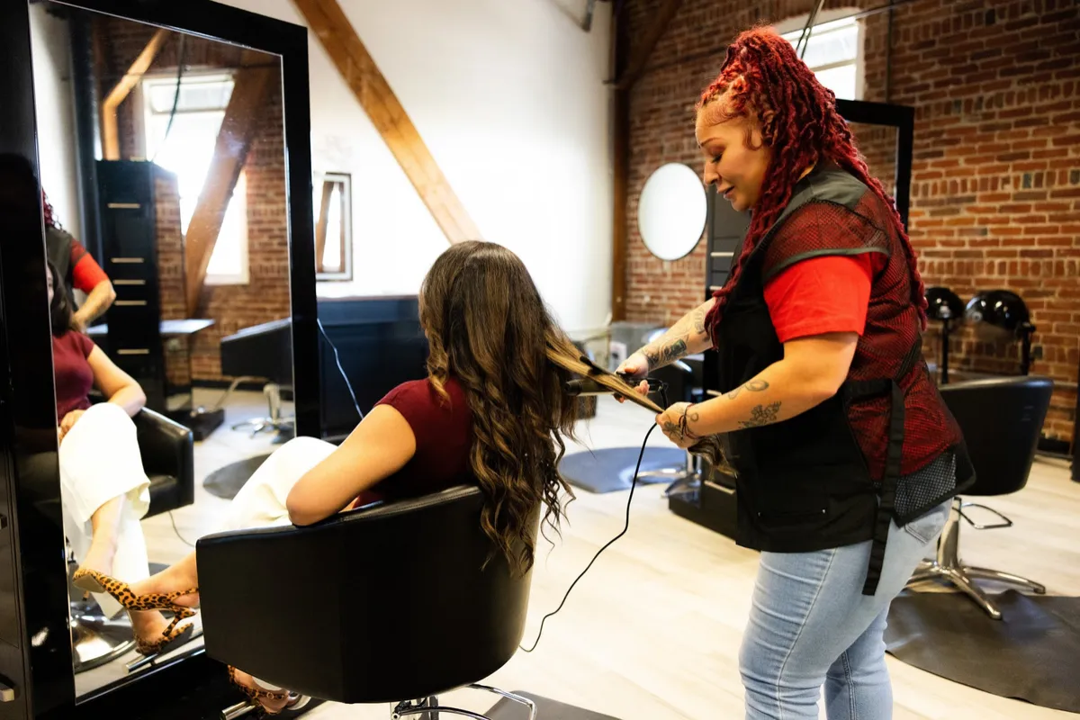 Stylist curling a client's hair at her station