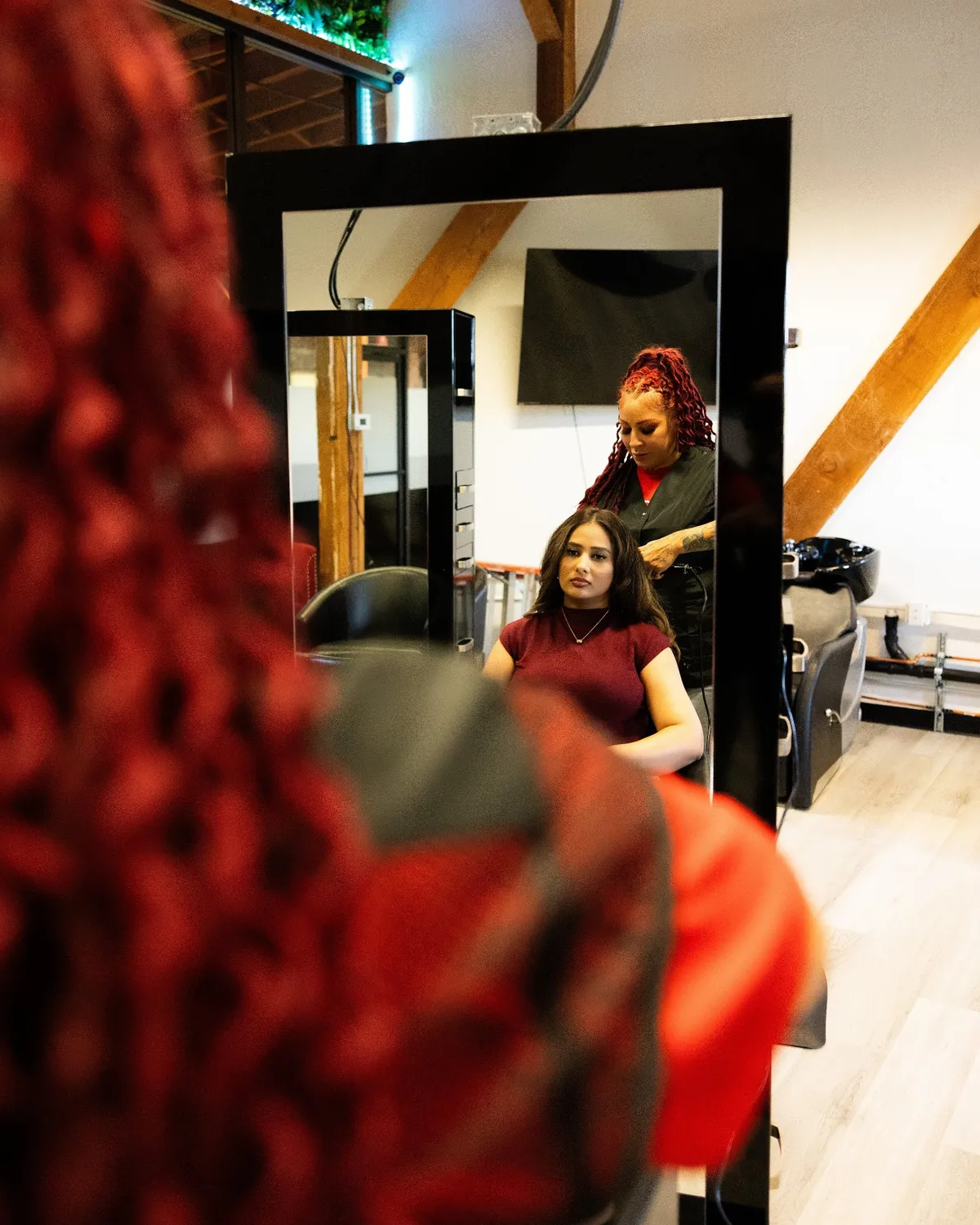 Detail of a stylist at work, red braids in the foreground