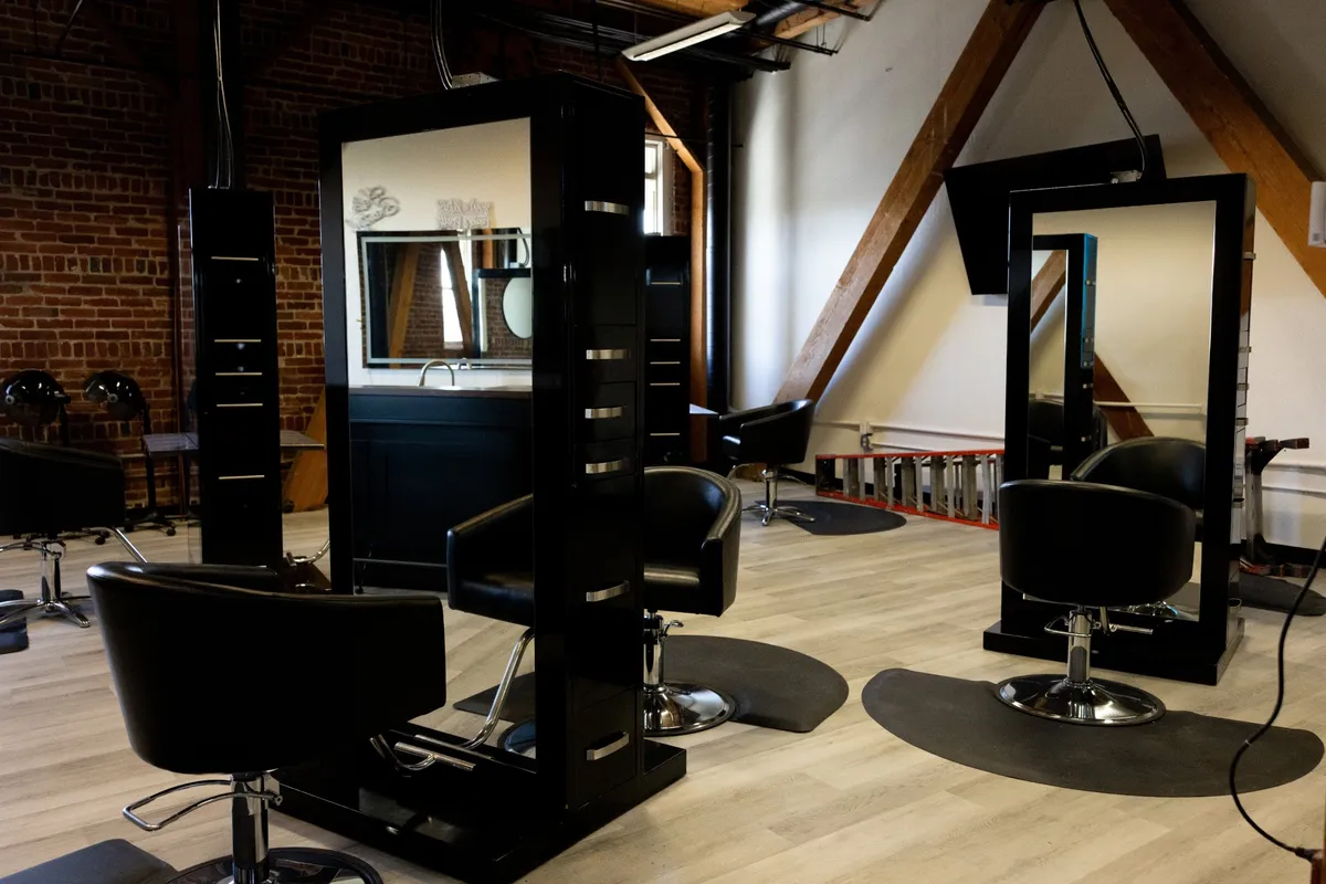 The open salon floor with black stations under timber beams