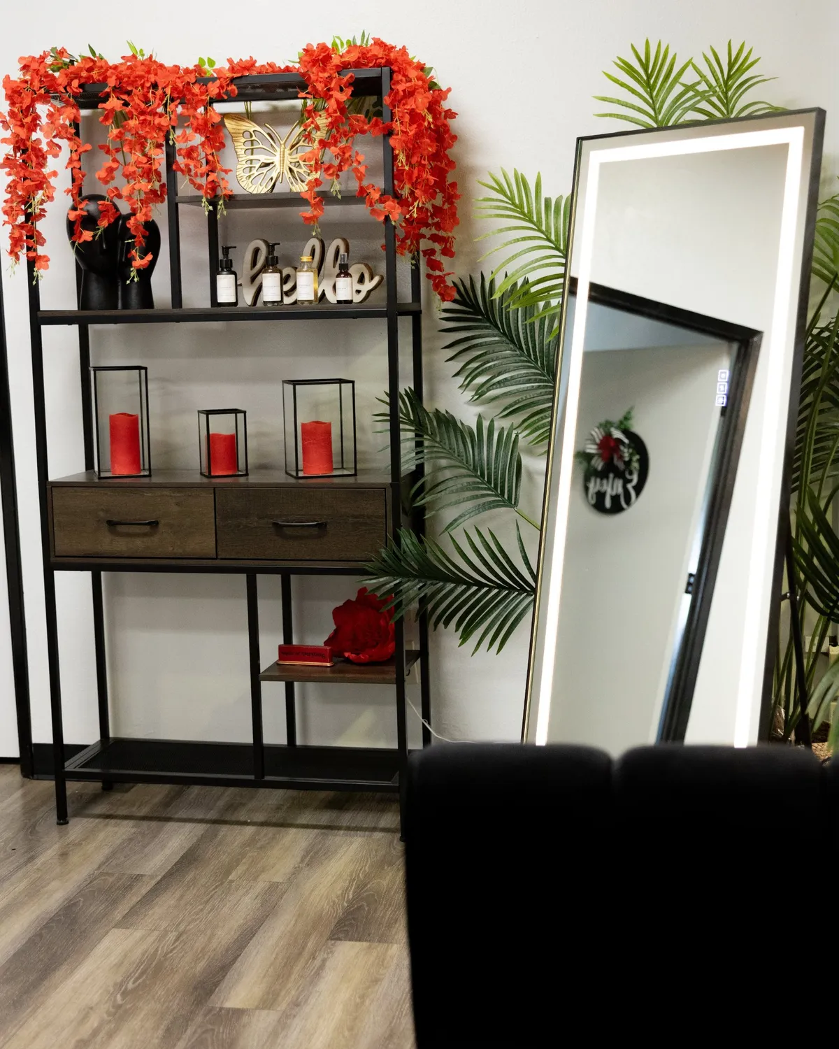 Shelf with red candles and florals beside a lit mirror