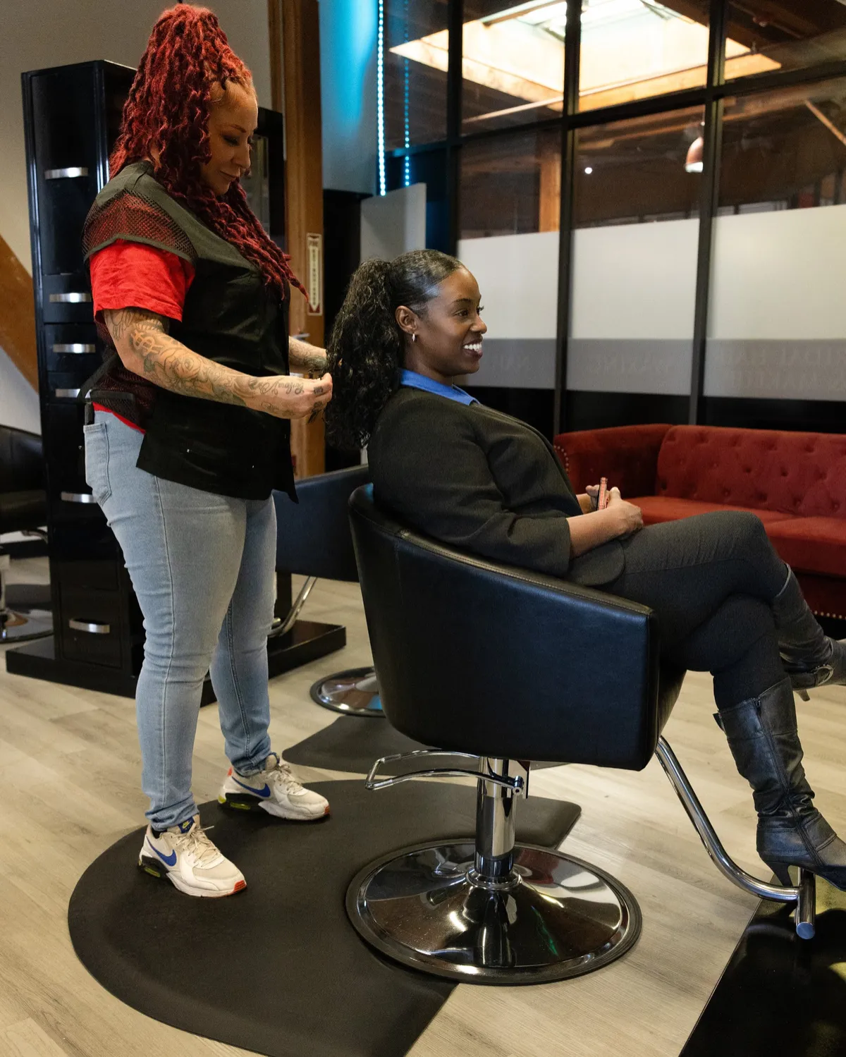 A smiling client in the chair while a Style City stylist styles her ponytail