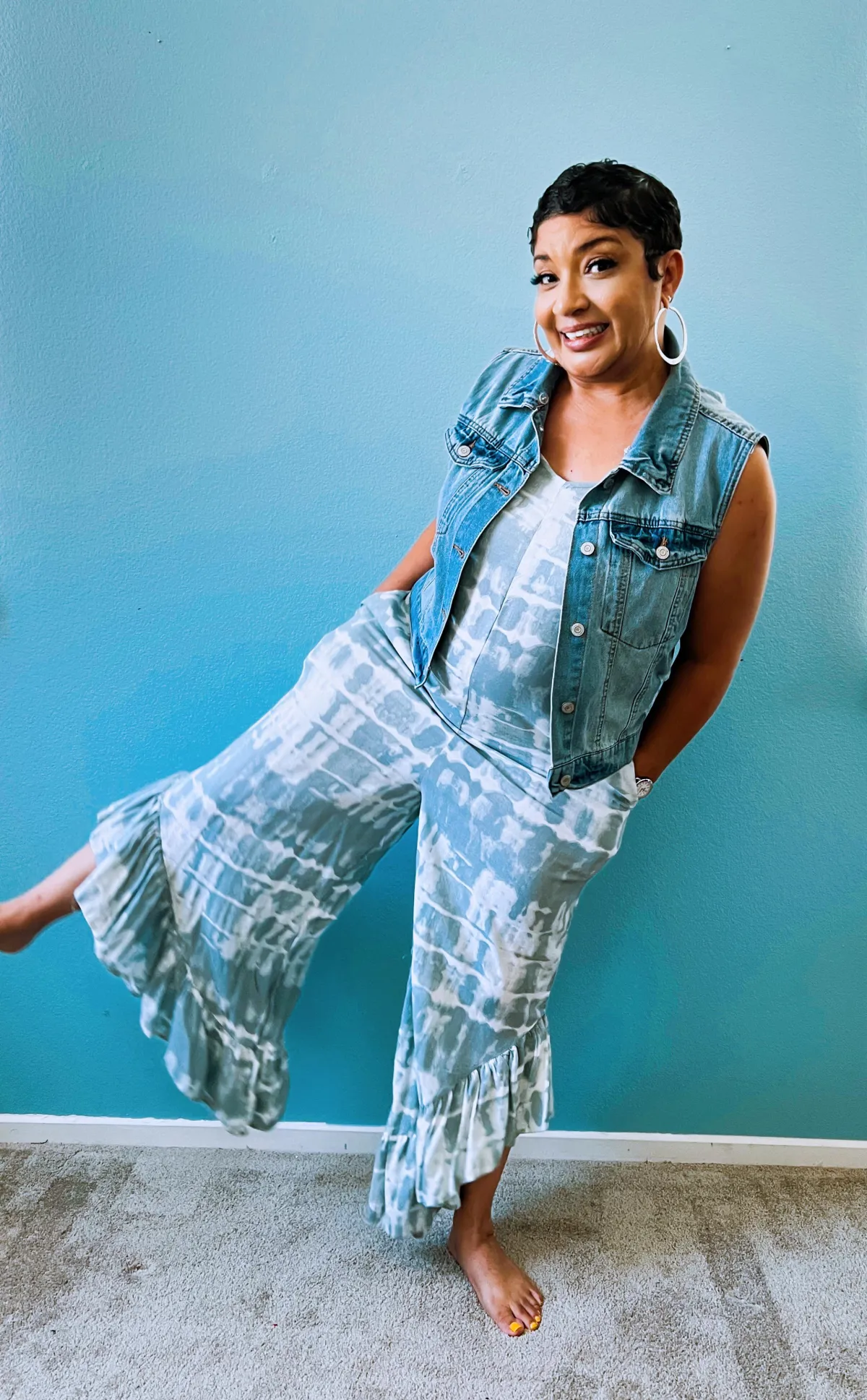 A warm, friendly art teacher kneeling beside two preschoolers as they create collages with colorful paper and glue. The classroom is filled with children’s artwork, and the teacher gently encourages the children, who are focused and smiling.